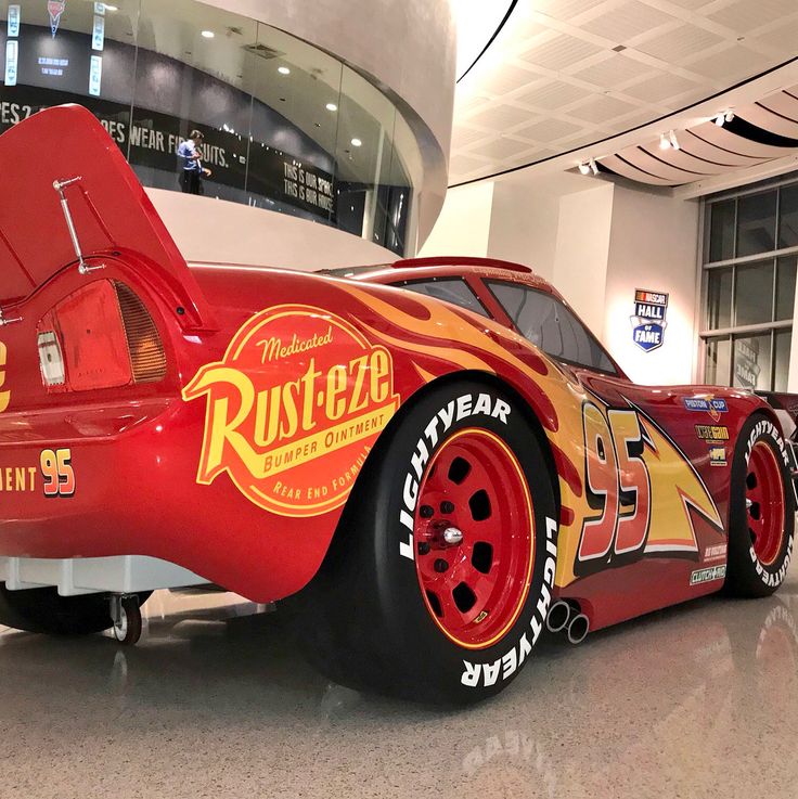 a red race car with flames painted on it's side in a museum lobby