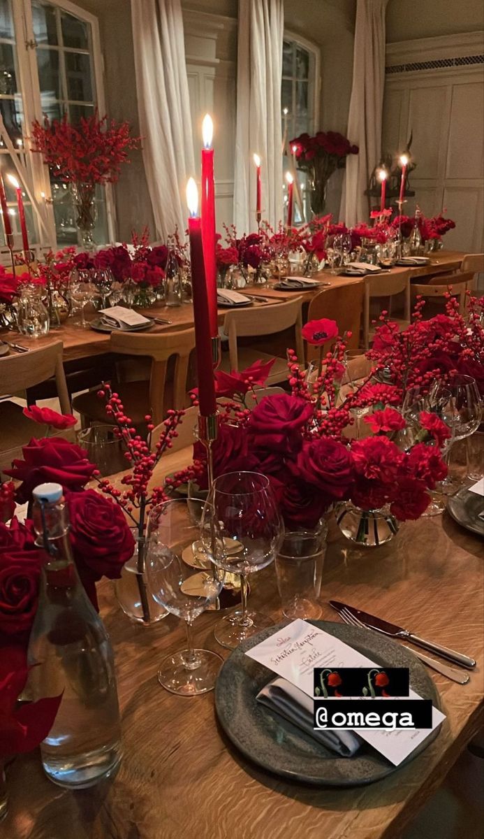 a long table is set with red roses and candles for an elegant dinner or party