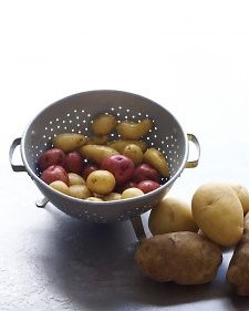 potatoes in a colander next to other vegetables