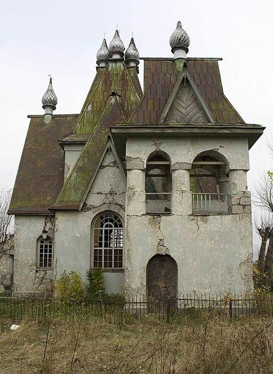 an old abandoned house with two chimneys and three windows on the top floor, surrounded by tall grass