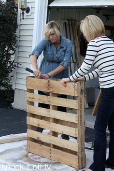 two women are working on a wooden crate