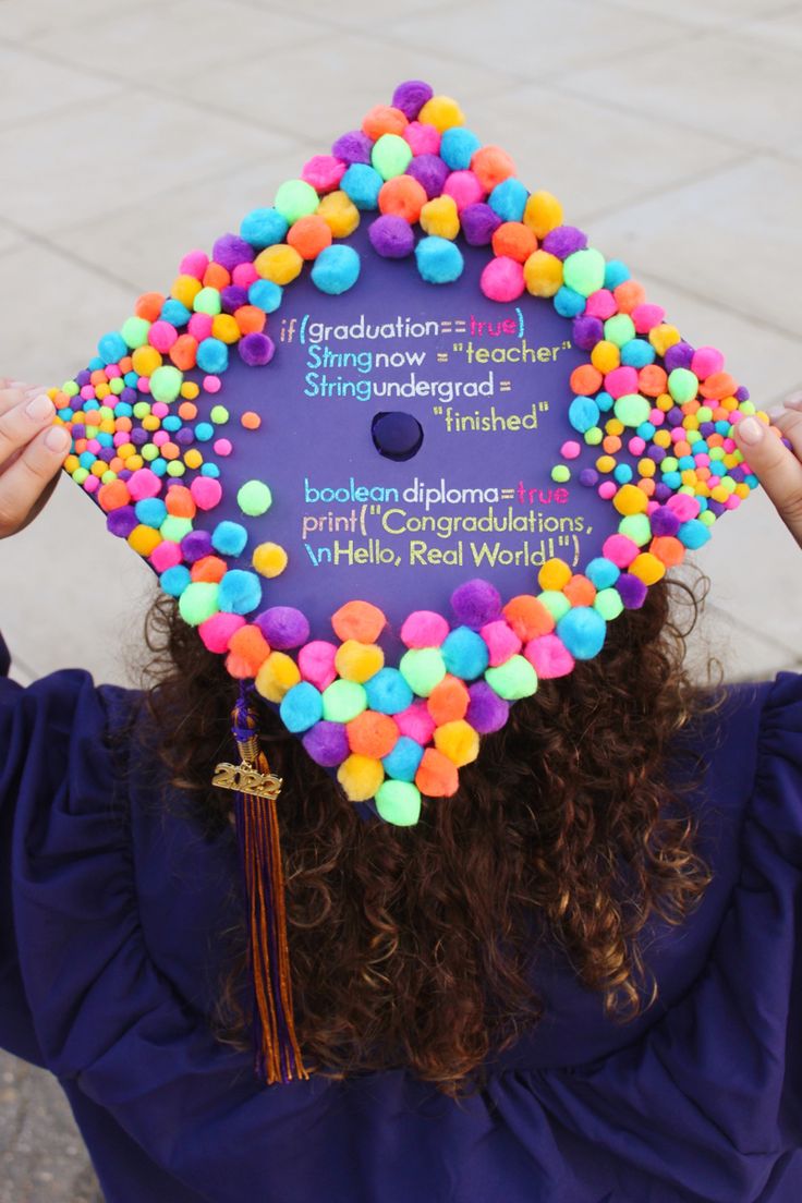 a woman wearing a purple graduation cap with colorful pom - poms on it