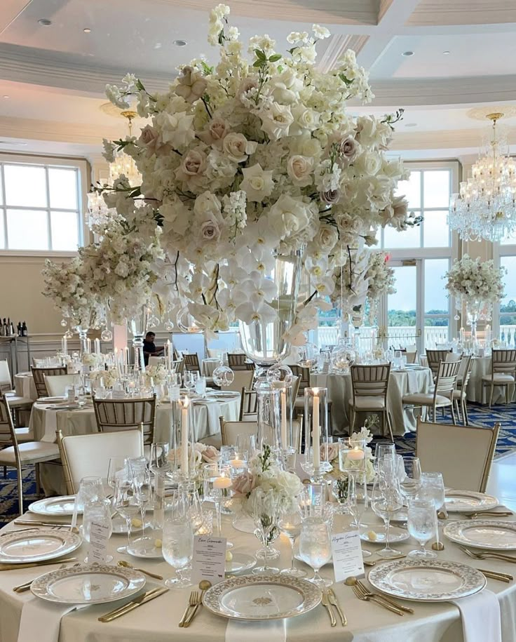 a table set up for a formal dinner with flowers and candles on the centerpieces