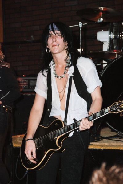 a man in white shirt playing guitar on stage