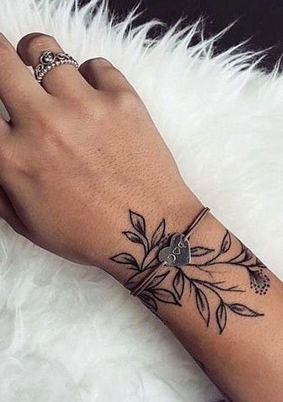 a woman's hand with a flower tattoo on her left wrist and the other arm