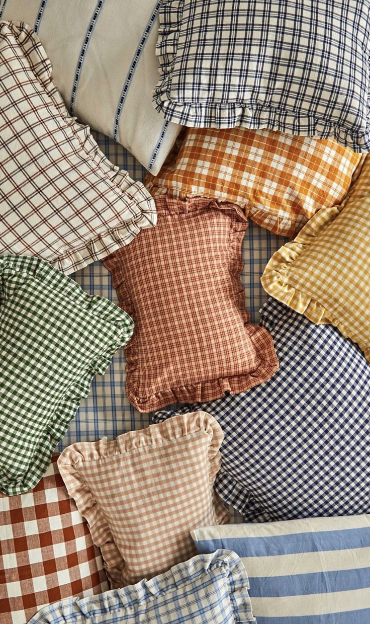 many pillows are arranged on top of each other in different colors and patterns, including checkered