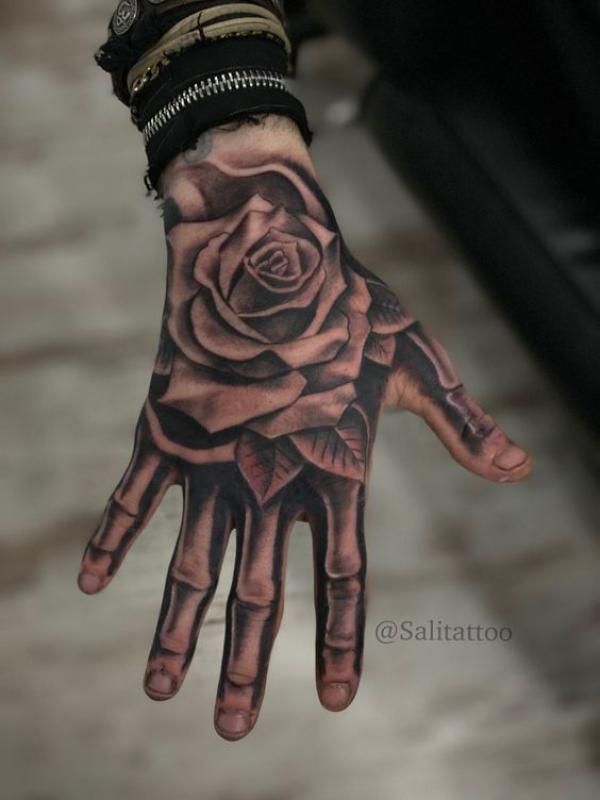 a person's hand with a rose tattoo on it