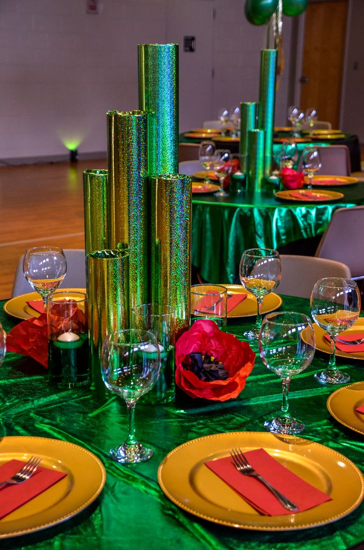 the table is set with green and yellow plates, silverware, and red napkins