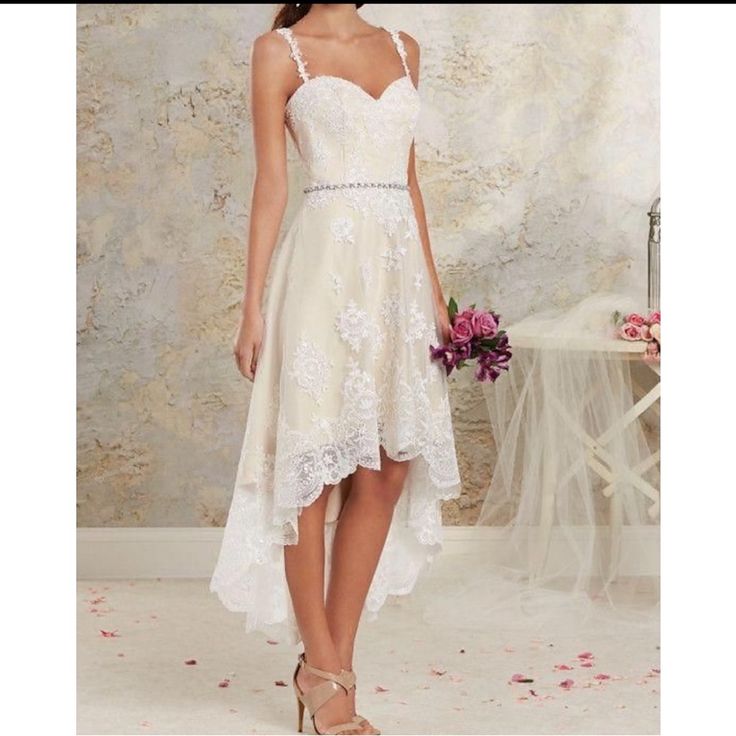 a woman in a white dress standing next to a table with flowers and a bouquet