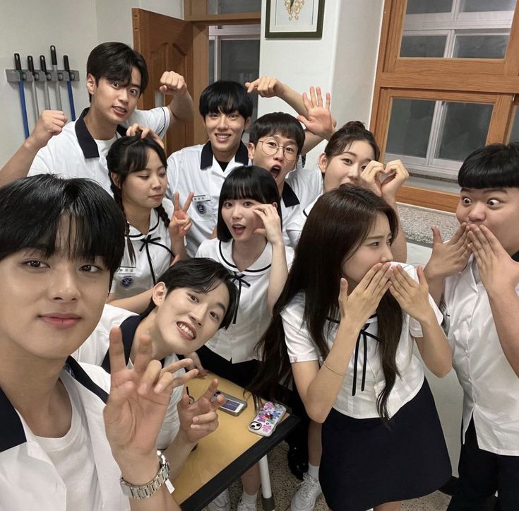 a group of young people standing next to each other in front of a desk with their hands up