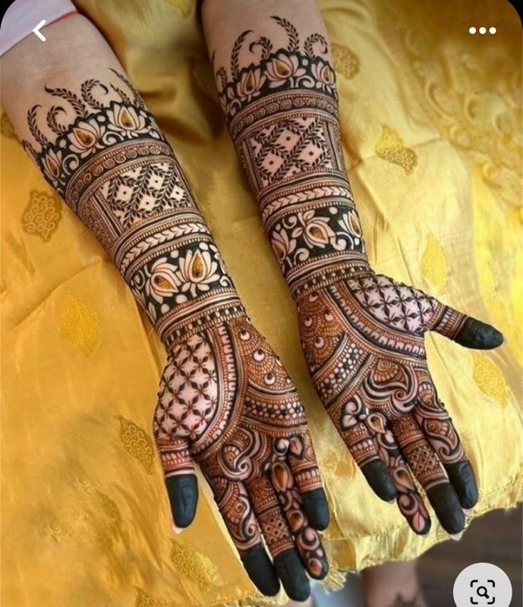 two hands with henna tattoos on them, one is showing off the intricate design