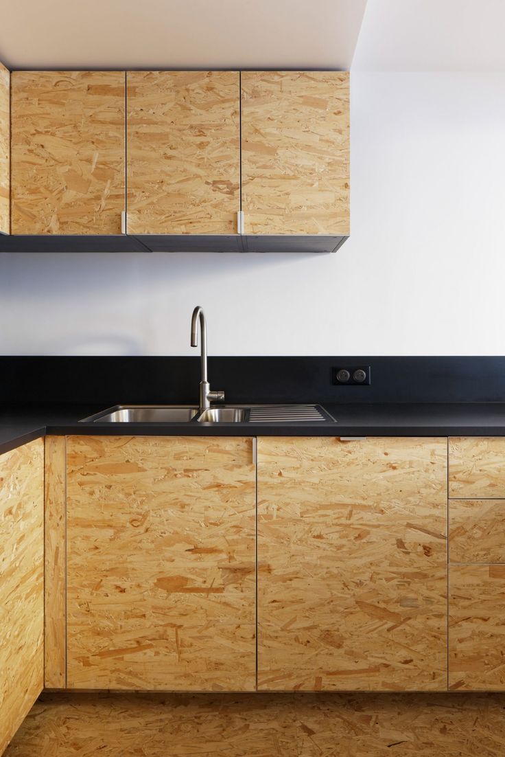 an empty kitchen with wooden cabinets and black counter tops on the wall, along with a stainless steel faucet