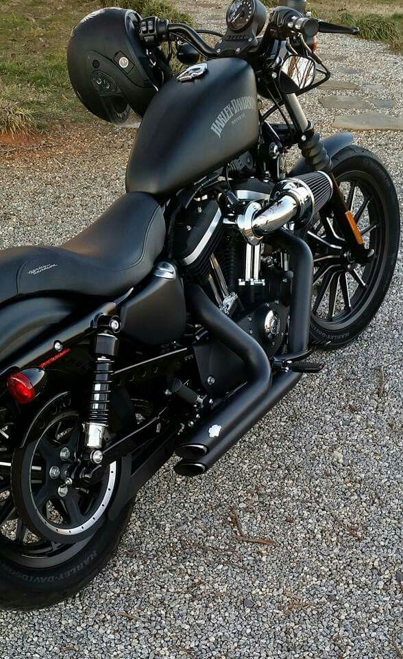 a black motorcycle parked on top of a gravel road