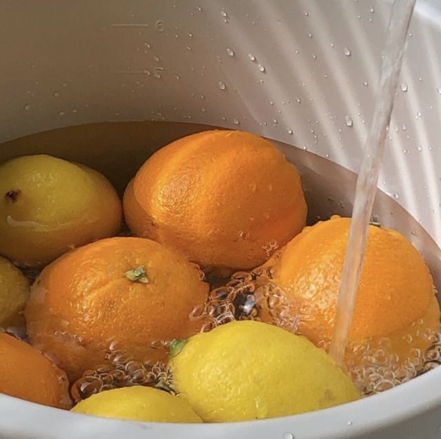 a bucket full of lemons and oranges with water coming out of the top