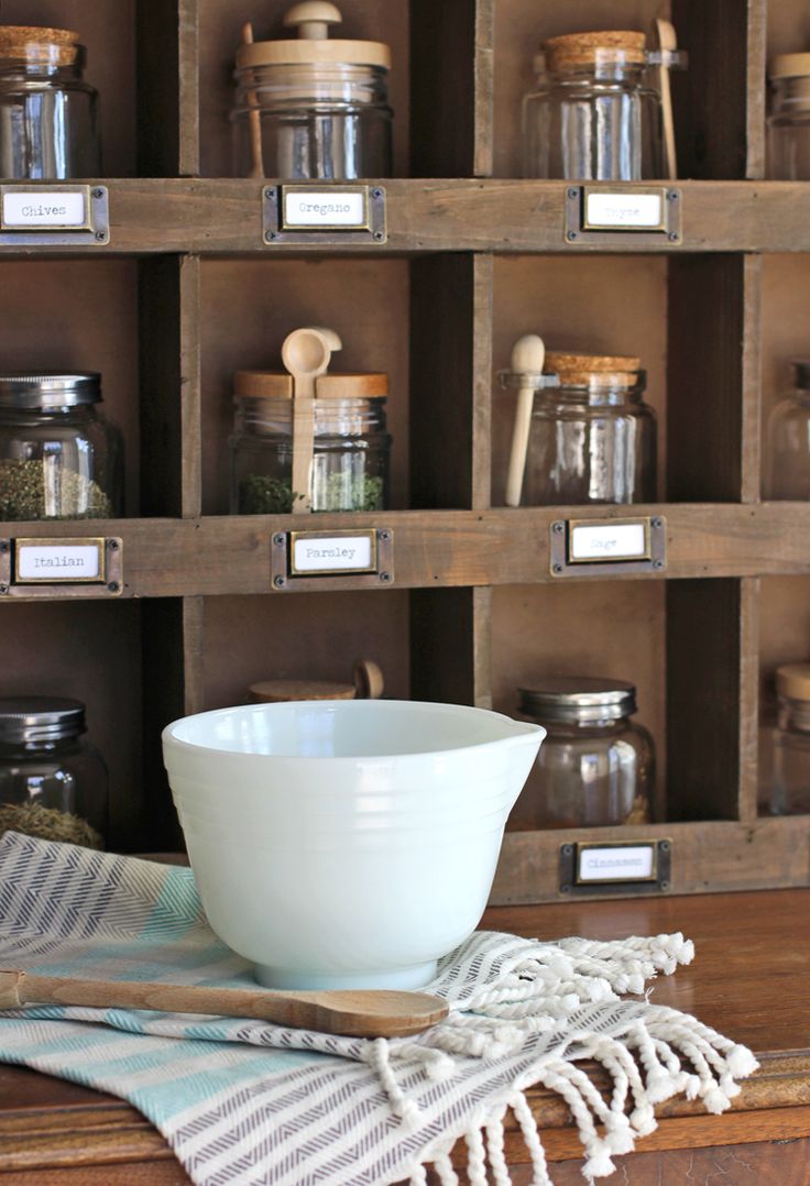 a white bowl sitting on top of a wooden table next to jars and spoons