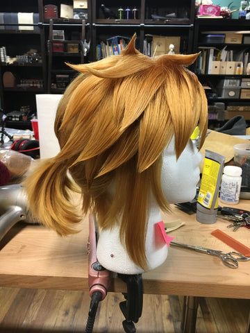 a wig with long hair sitting on top of a wooden table next to scissors and other items