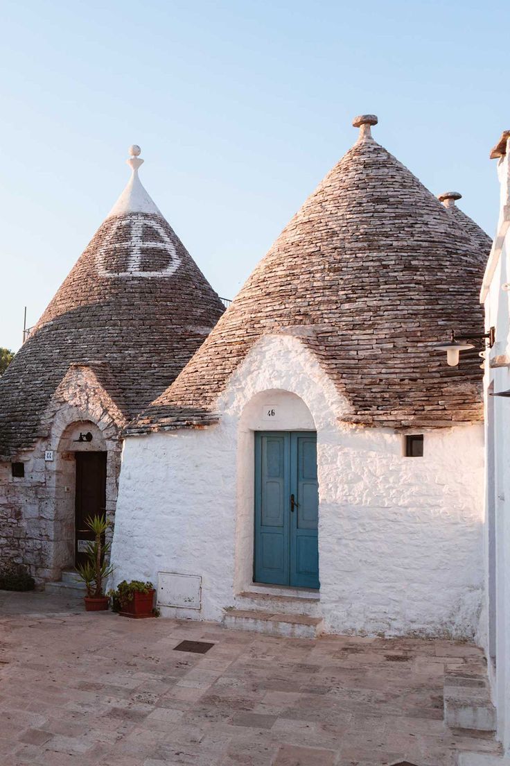 an old white building with two blue doors and three stone domes on the side of it