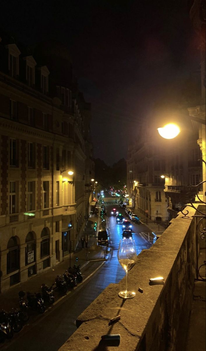 a city street at night with motorcycles parked on the side and people walking down the sidewalk