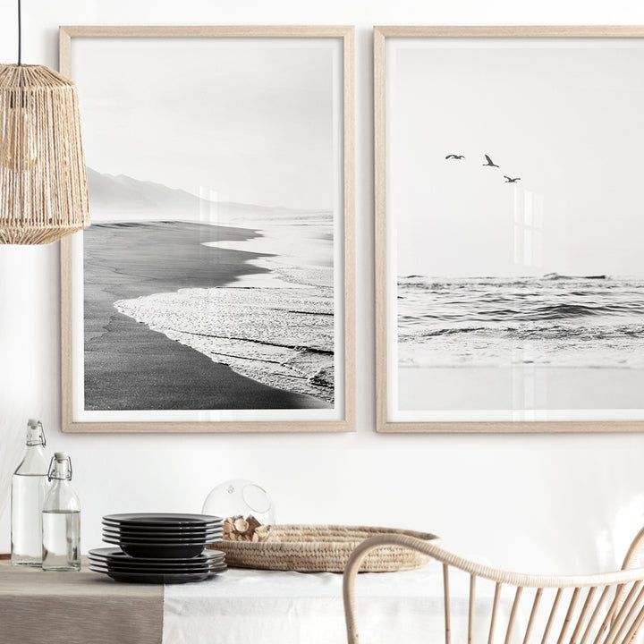 two black and white pictures hanging on the wall above a dining room table with chairs