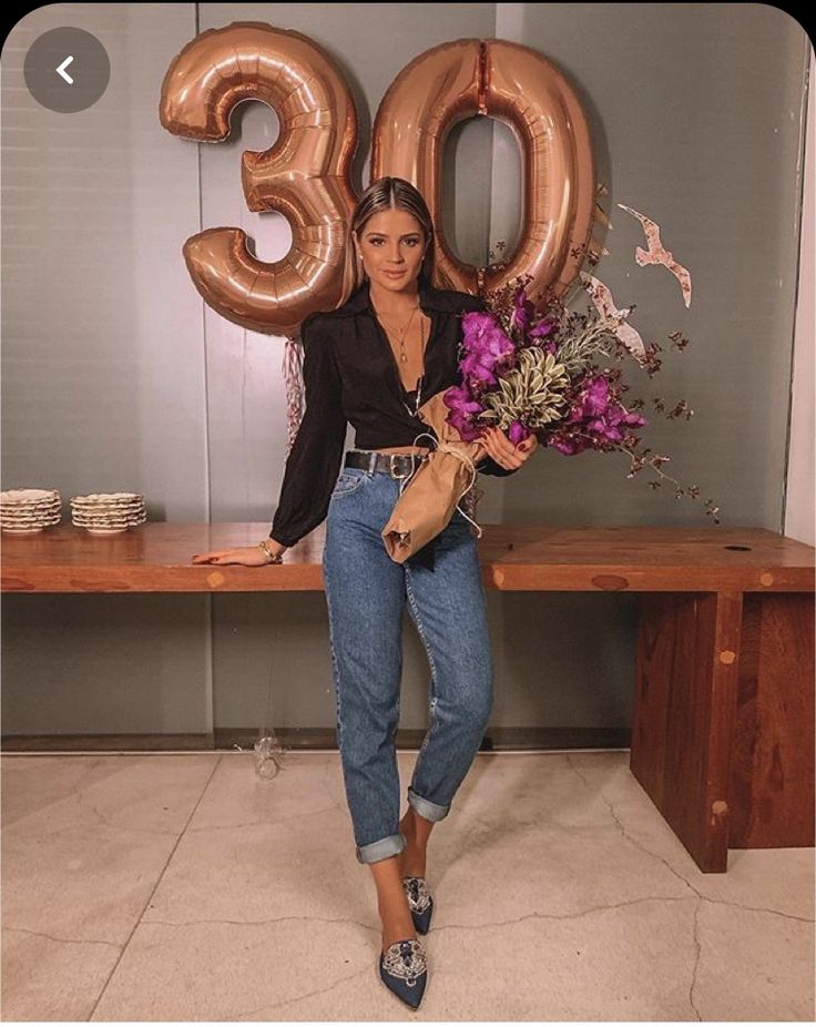 a woman standing in front of a table with flowers and balloons that say 30 on it