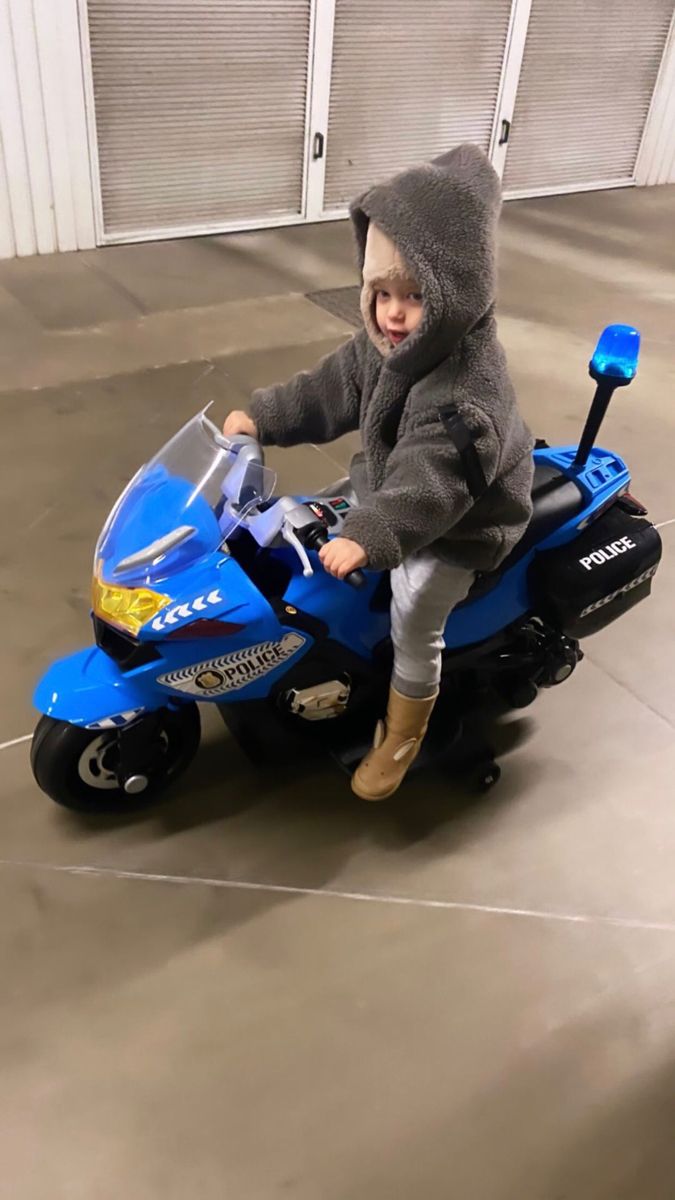 a young child riding on the back of a blue toy motorcycle