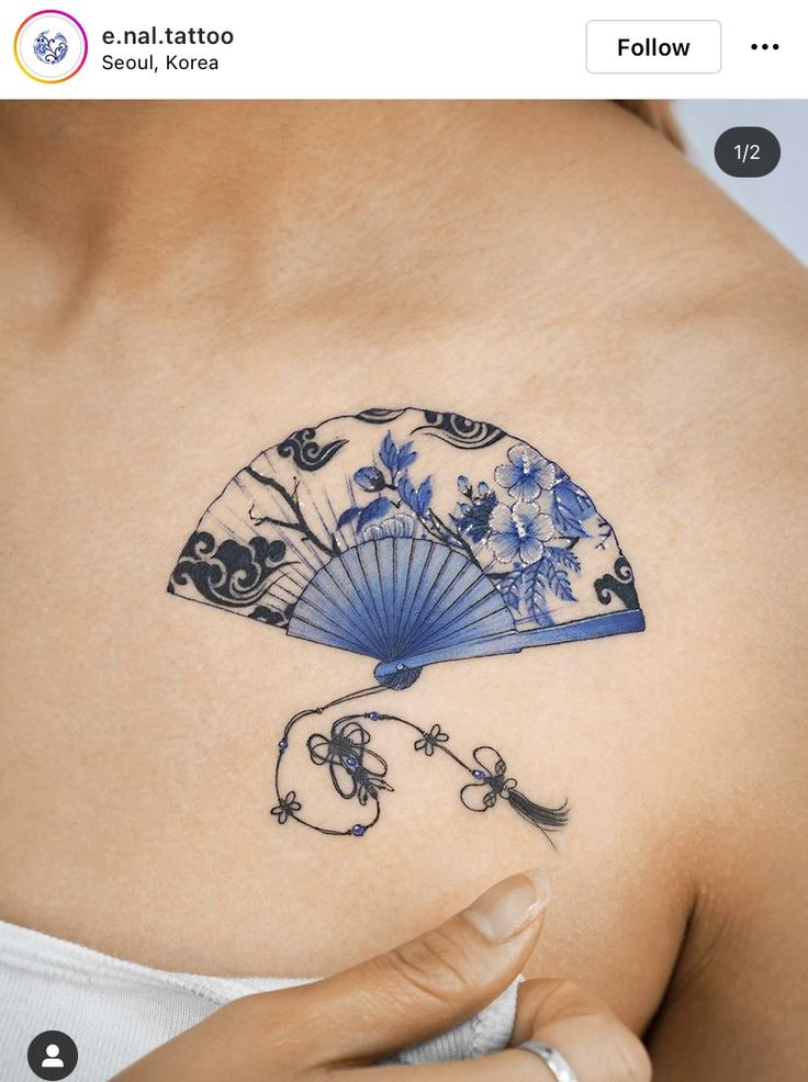 a woman with a tattoo on her shoulder holding a blue fan in front of her chest