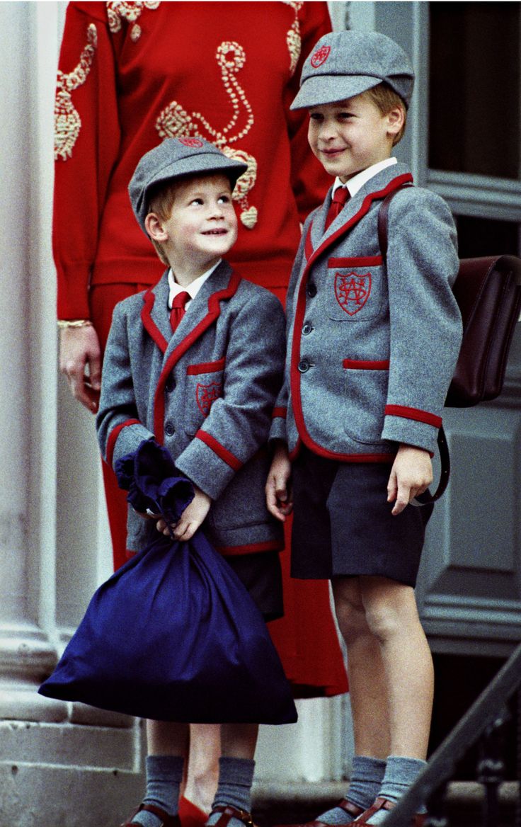 two young boys standing next to each other in front of an older man and woman