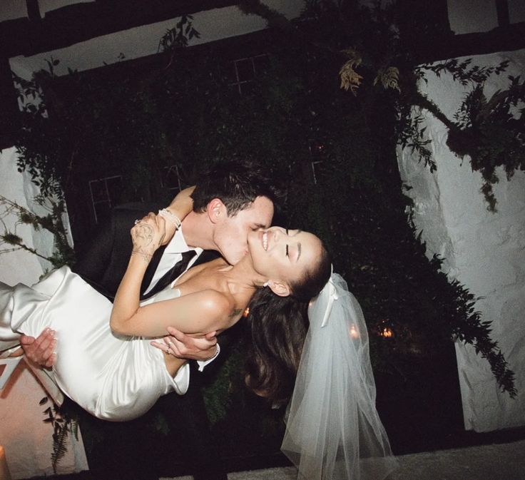 a bride and groom kissing in front of a candle lit area at their wedding reception