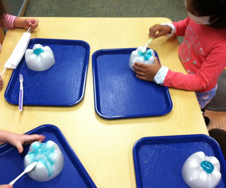 three children are sitting at a table with blue trays and white balloons on them