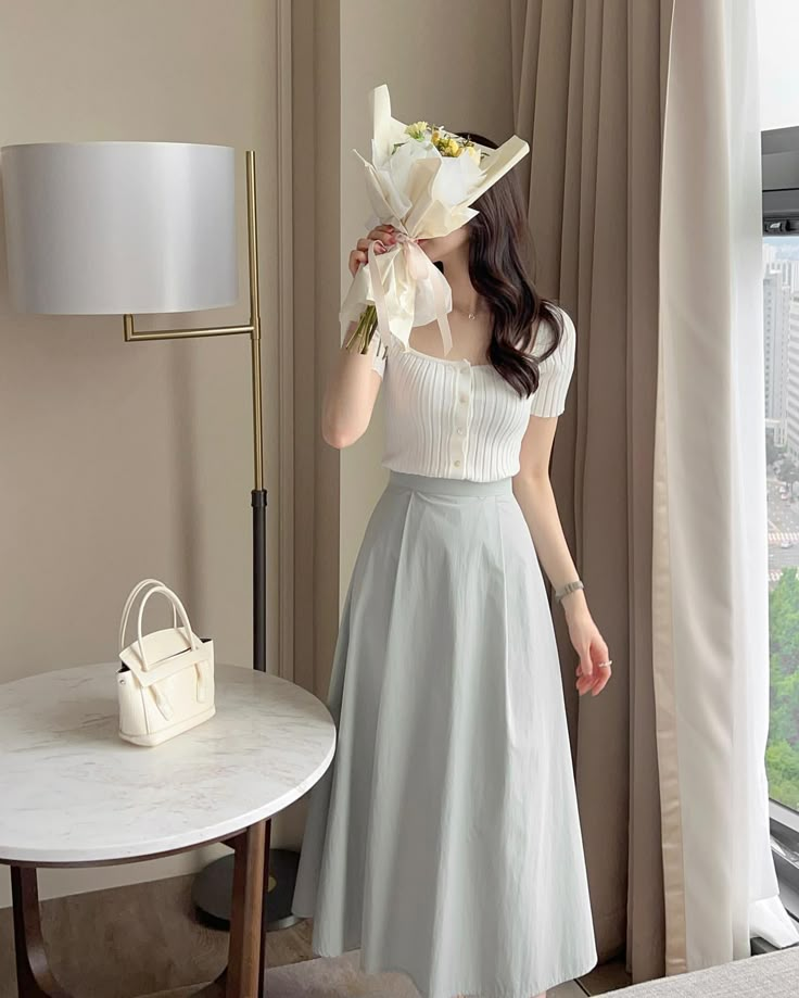 a woman in a white dress is standing near a table with a purse on it