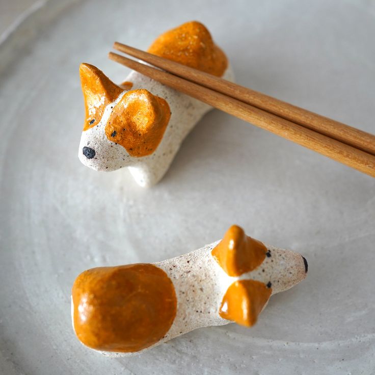 two small dog figurines on a plate with chopsticks