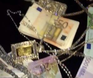 several different types of money are being displayed on a table with chains and other items