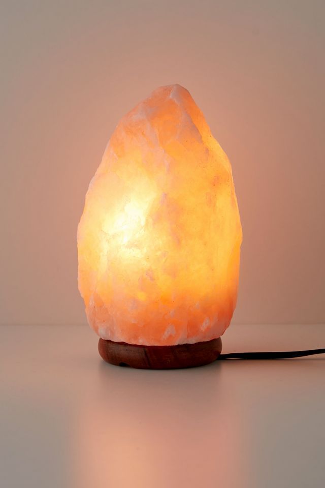 a himalayan rock lamp on a wooden base with a white light shining in the background