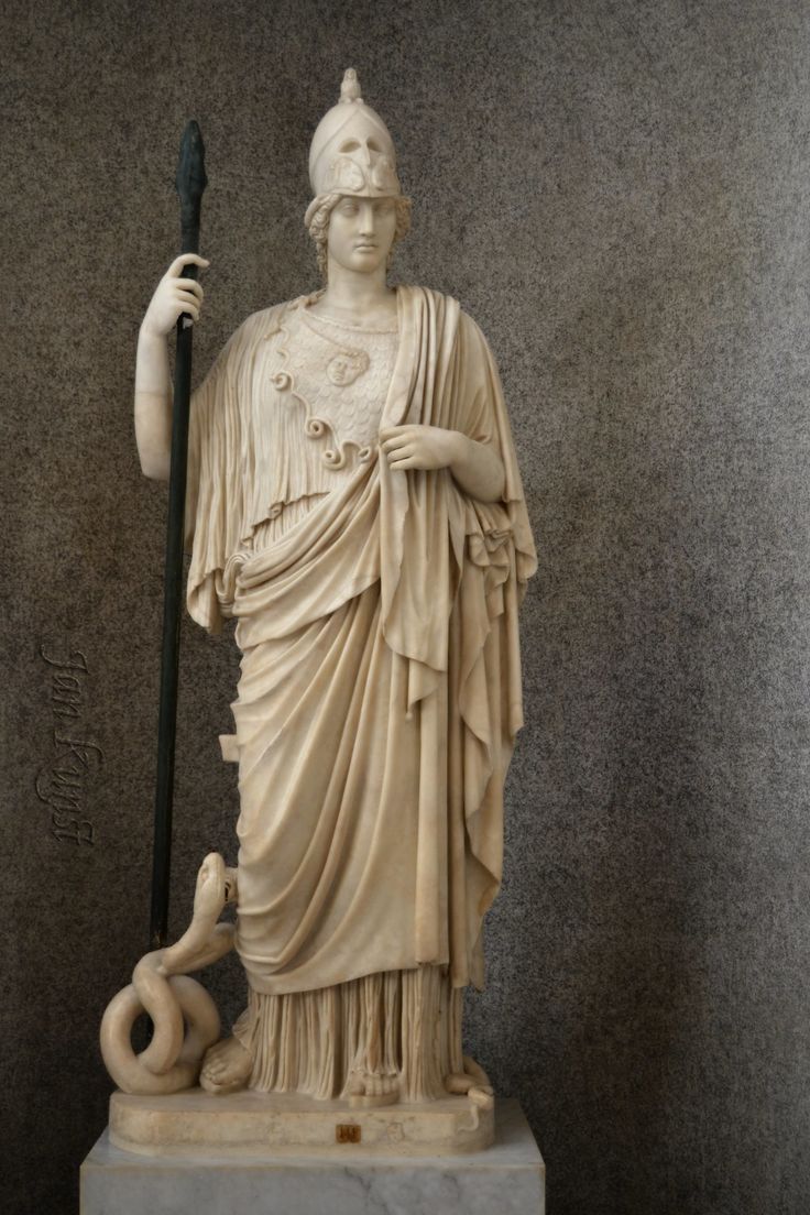 the statue is holding a staff and standing next to a snake