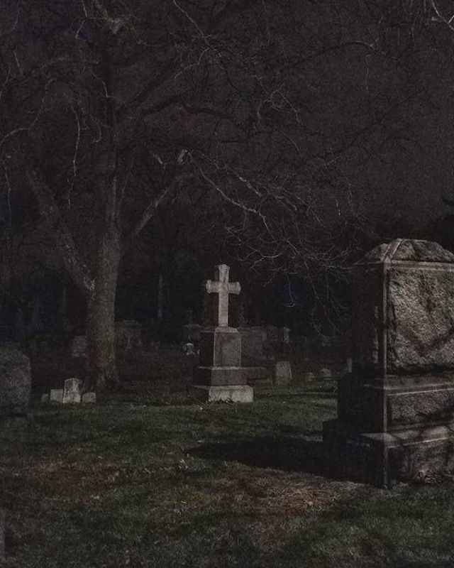 an old cemetery at night with tombstones in the foreground and trees to the side