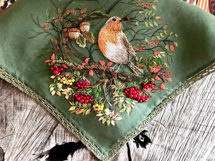 a green pillow with a bird and berries on it