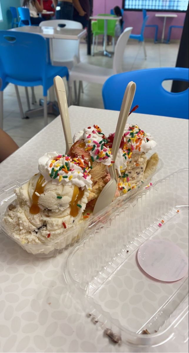 an ice cream sundae with sprinkles in a plastic container on a table