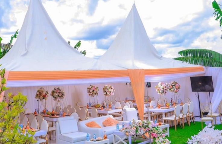 an outdoor tent set up with white chairs and flowers on the tables for a wedding reception