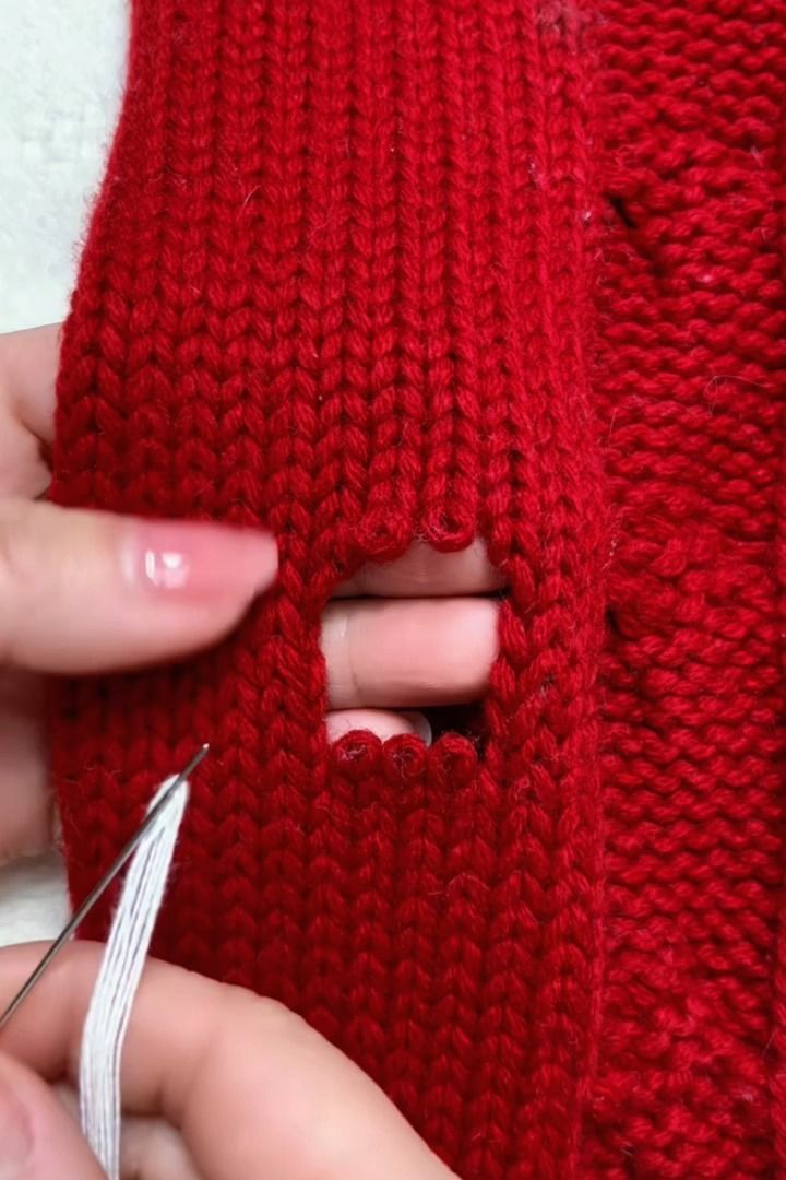 someone is cutting through the side of a red knitted sweater