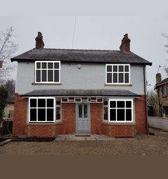 a grey house with white windows and two chimneys