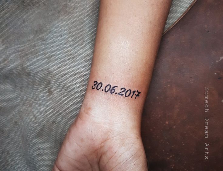 a person's wrist with a date tattooed on the left side of their arm