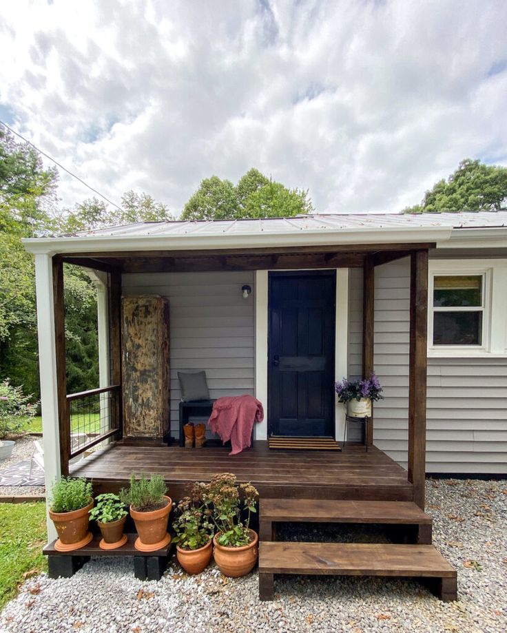 a small house with potted plants on the porch