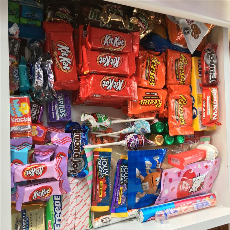 a shelf filled with lots of candy on top of a white counter next to a wall