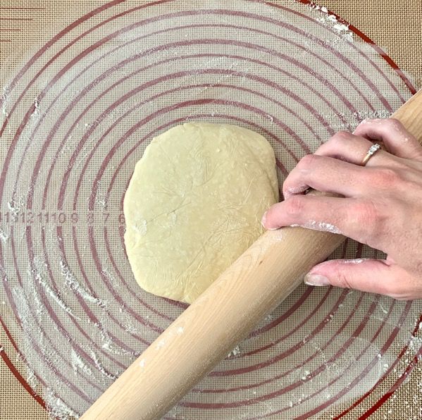 a person rolling dough on top of a glass plate