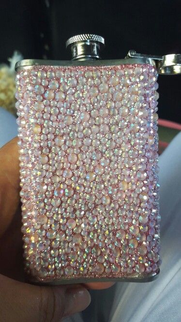 a person holding a pink flask covered in crystals