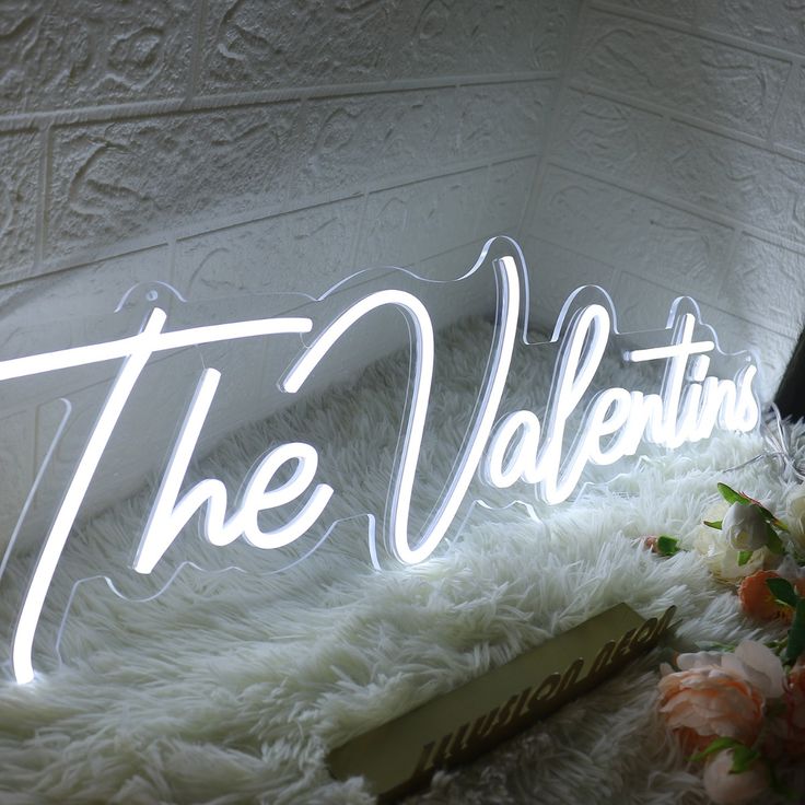 the valentine's sign is lit up with flowers