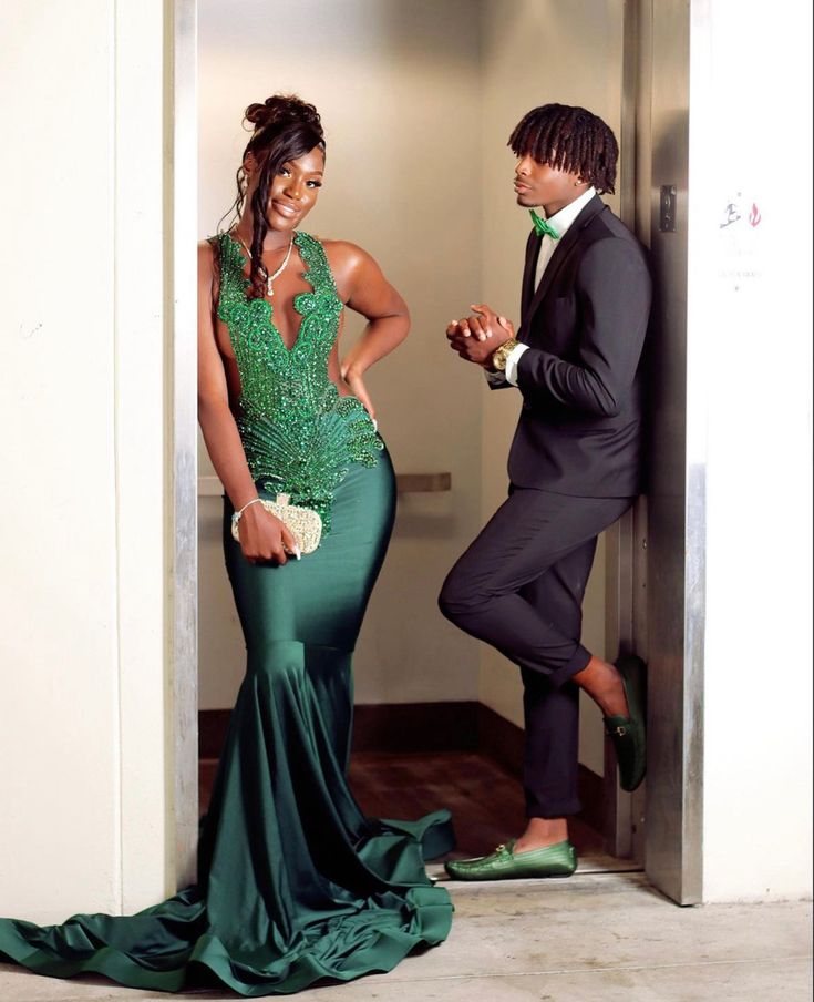 a man and woman in formal wear standing next to an open door with their hands on each other's hips