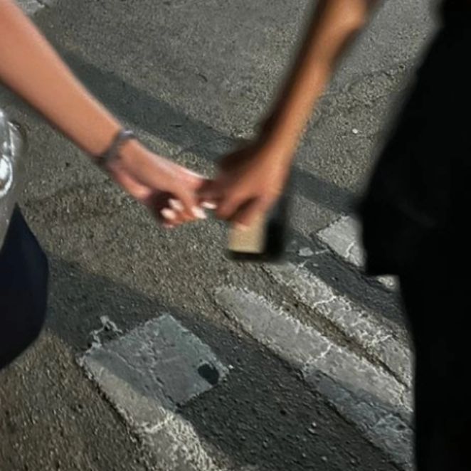 two people are walking down the street holding onto each other's hand while one person holds something