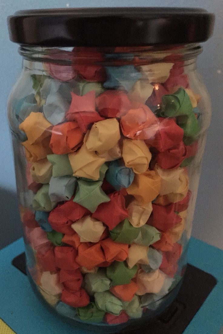 a glass jar filled with colorful gummy bears on top of a blue table cloth