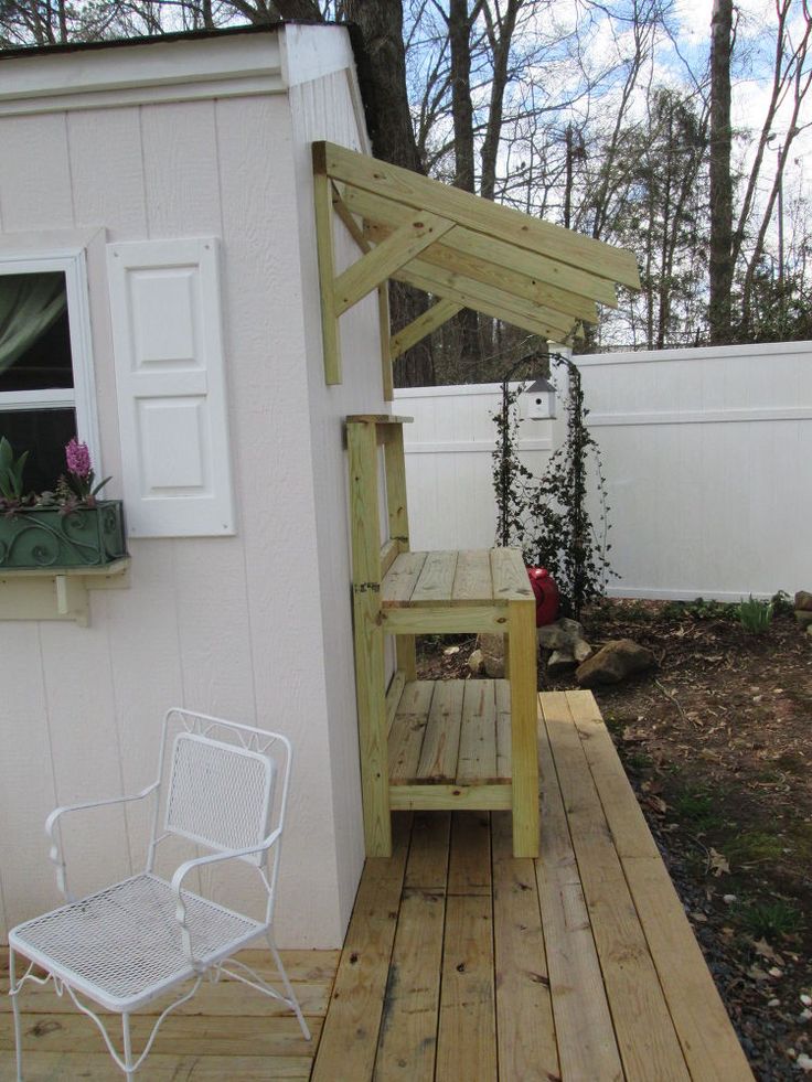 a white chair sitting on top of a wooden deck next to a small building with windows